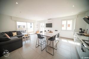 a kitchen and living room with a couch and a table at Les Embruns - Mer - Terrasse in Le Grau-du-Roi