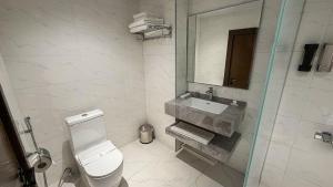 a white bathroom with a toilet and a sink at Burj Al Salam Hotel in Al ‘Alwīyah