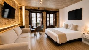 a bedroom with a bed and a couch and a table at Rua Mayor MSuites in Salamanca