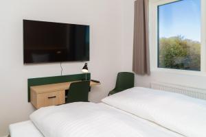 a hotel room with two beds and a desk and a tv at Easy Stay Næstved in Næstved
