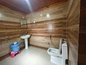 a bathroom with wooden walls and a toilet and a sink at Himalaya Vista - 1km Uphill Hike from Main Road in Harsil