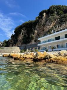 a building on the side of a mountain next to the water at Hotel Kristera in Vlorë