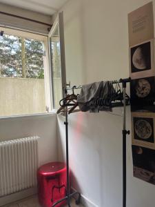 a stand in a room with a window and a red stool at Chambre confortable in Saint-Maur-des-Fossés