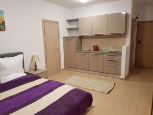 a bedroom with a purple and white bed and a kitchen at De Silva Residence in Mamaia