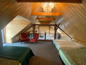 a attic room with two beds and chairs and a chandelier at Studio 611 in Třebíč