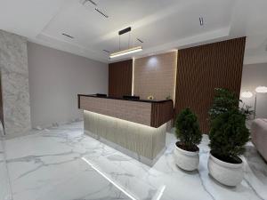 a lobby with a reception desk and two potted plants at Vaishnavi Beacon Hotel Patna in Patna