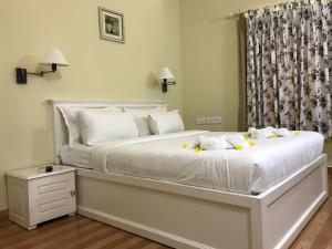 a bedroom with a white bed with yellow flowers on it at Daffodils Spice Court in Cochin