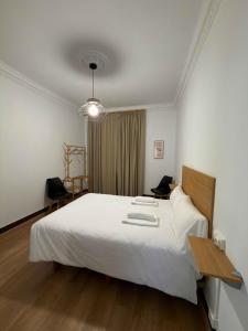 a bedroom with a large white bed and a desk at LA CASA DEL RÍO - A 13 kilómetros de Santiago in Sigüeiro