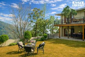 a patio with chairs and a table in a yard at StayVista at Cedar Crest Villa with Bonfire, Valley View in Kasauli