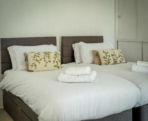 two twin beds with towels on top of them at Foresters Cottage, Dalry in Dalry