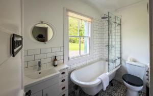 a bathroom with a tub and a toilet and a sink at Foresters Cottage, Dalry in Dalry +32 photos