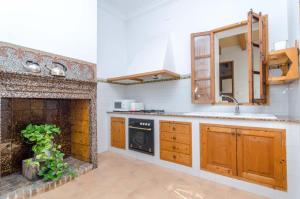 a kitchen with wooden cabinets and a fireplace at Can Romaguera in Algaida