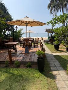 a wooden deck with tables and an umbrella on the beach at Endlessblue Resort Kalametiya in Kalametiya