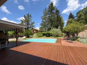 a wooden deck with a swimming pool in a yard at Villa aux oiseaux in Biganos +12 photos