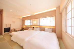 a large white bed in a room with windows at Richmond Hotel Kagoshima Kinseicho in Kagoshima