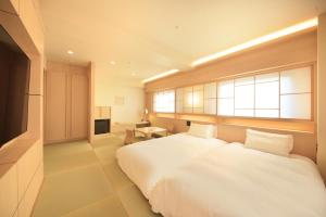 a bedroom with a large white bed and a window at Richmond Hotel Kagoshima Kinseicho in Kagoshima