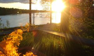 una hoguera frente a un lago con la puesta de sol en B&B Pinus, en Mäntyharju