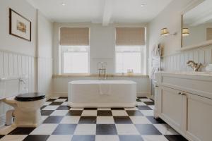 a bathroom with a white tub and a checkered floor at The William Cecil in Stamford +45 photos