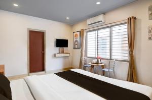 a bedroom with a bed and a table and a window at Hotel Pratishtha in Guwahati