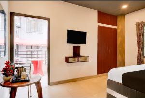 a bedroom with a bed and a table and a tv at Hotel Pratishtha in Guwahati +15 photos
