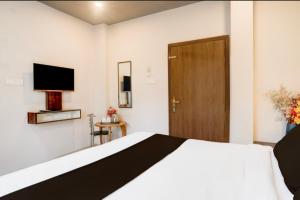 a bedroom with a bed with a television and a door at Hotel Pratishtha in Guwahati