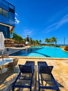 a swimming pool with two chairs and a lighthouse at Villa Nautilus Be Happy in Fortaleza