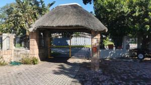a gazebo with a straw roof and a gate at Junior Suite with Pool View - in Port Elizabeth +11 photos