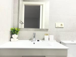a white bathroom with a sink and a mirror at Apartamento con patio cerca de la playa in Bueu +24 photos