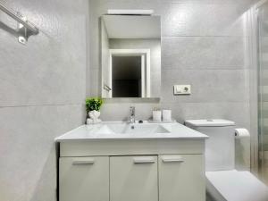 a white bathroom with a sink and a toilet at Apartamento con patio cerca de la playa in Bueu