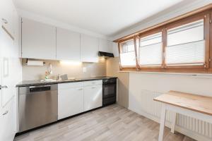 a kitchen with white cabinets and a wooden table at Thimo's Lakeview - Sunset near Interlaken in Leissigen