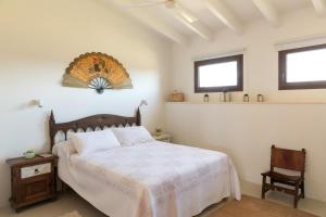 a bedroom with a bed and a chair and two windows at Finca Son Vidal in Llucmajor