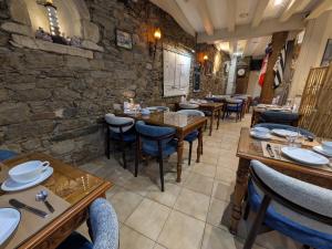 a restaurant with tables and chairs and a stone wall at Hotel des Abers in Saint Malo