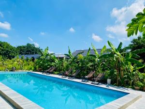 a swimming pool with chairs and palm trees at Rocky Mountain Ecology in Xuân Sơn
