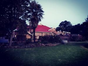 a house with a fence and a tree in a yard at Bella - Rosa in Ficksburg