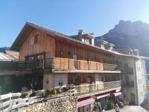 ein großes Holzgebäude mit einem Berg im Hintergrund in der Unterkunft Ciasa Savoy in Vigo di Fassa