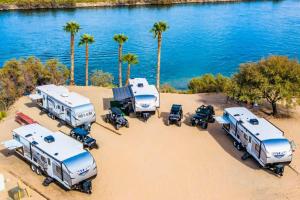 a group of rvs parked on the beach with palm trees at Pirate Cove Resort in Needles