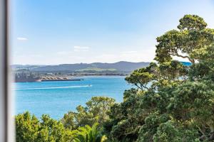 a view of the ocean with a boat in the water at Reotahi Bolthole in Whangarei Heads