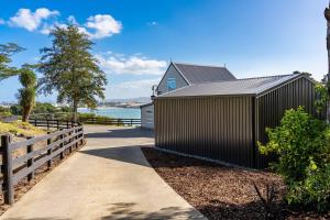 a house with a black fence next to a sidewalk at Reotahi Bolthole in Whangarei Heads +17 photos