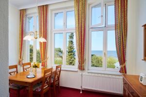 a dining room with a table and chairs and windows at Appartement 06 Strandvillen Wald & See in Zinnowitz