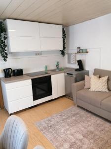 a kitchen with white cabinets and a couch in a living room at Thomas Haus 1 in Günzburg