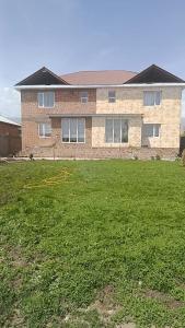 a brick house with a large lawn in front of it at SunLake House in Balykchy