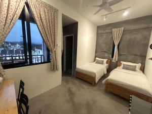 a bedroom with two beds and a large window at Silvan Garden Retreat in Tanah Rata