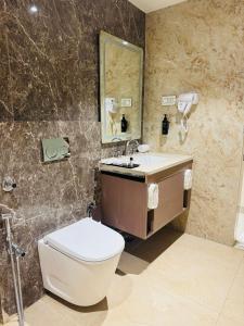 a bathroom with a toilet and a sink and a mirror at Vetiver Grand in Jabalpur