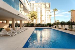 a swimming pool with lounge chairs next to a building at Superior Calpe Pearl Beach in Calpe