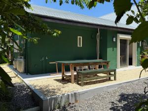 a picnic table in front of a green building at Green Rabbit House by private beach in Ishigaki Island