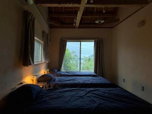 two beds in a small room with a window at Green Rabbit House by private beach in Ishigaki Island