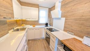 a kitchen with white counters and a wooden wall at Apartamento Mar y Encanto in Miami Platja +31 photos