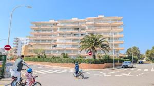 two children riding bikes on a street with a large building at Apartamento Mar y Encanto in Miami Platja
