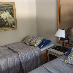 a room with two beds and a table with a lamp at Yli-Kaitala Holiday Resort Tuuliviiri in Savio