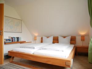 a bedroom with a wooden bed with white sheets at Villa Pepita in Kaltenhof